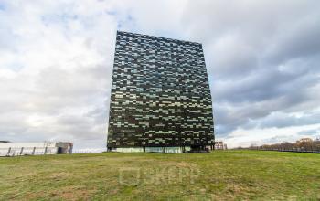 Exterior view of the modern office building for rent at Jonkerbosplein 52, Nijmegen, featuring a checkerboard facade and surrounding green space.