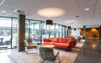 Modern office space for rent at Jonkerbosplein 52 in Nijmegen featuring a stylish lounge area with comfortable seating and large windows.