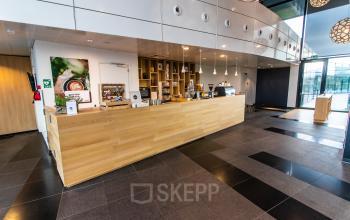 Modern office space at Jonkerbosplein 52, Nijmegen features a sleek wooden counter ideal for a reception area, available for rent as part of attractive office space rental offerings.