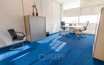 Bright office space with blue carpet, modern furniture, and natural light at Jonkerbosplein 52, Nijmegen, perfect for office space rental.