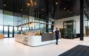 Modern office interior at Jonkerbosplein 52 in Nijmegen featuring a stylish coffee bar with people engaged in business activities, ideal for office space rental.