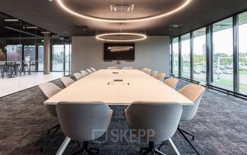 Spacious conference room at Jonkerbosplein 52, Nijmegen, featuring a large table surrounded by modern chairs under circular lights, available for office space rental.