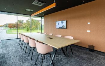 Modern conference room with a long wooden table and pink chairs at Jonkerbosplein 52 in Nijmegen, ideal for office space rental.