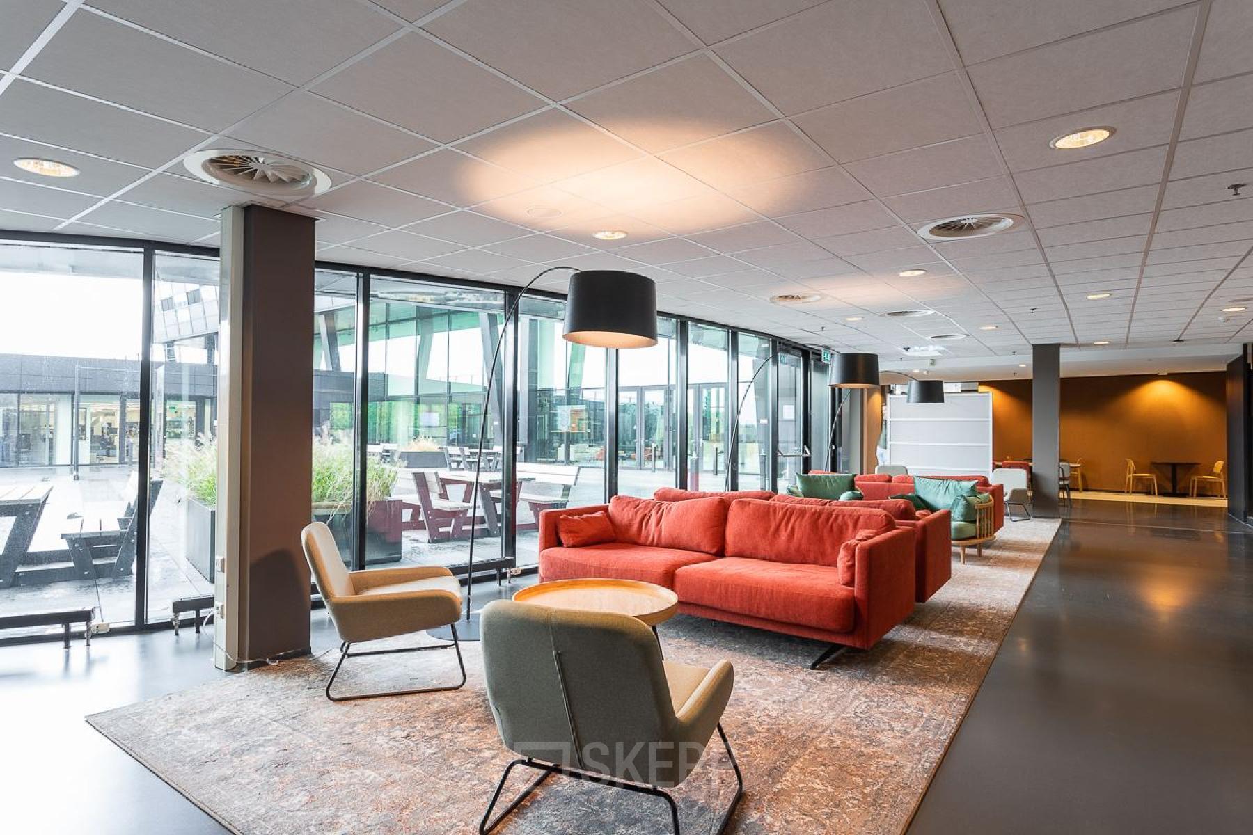 Modern office space for rent at Jonkerbosplein 52 in Nijmegen featuring a stylish lounge area with comfortable seating and large windows.