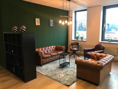 Cozy office space at Kerkenbos 1037, Nijmegen featuring leather seating, a green accent wall, and large windows, ideal for office space rental.