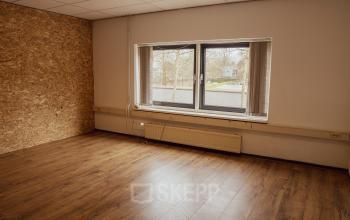 Interior office space at Abdis van Thornstraat 74, Oosterhout Nb, featuring a window overlooking the street and wooden flooring, available for office space rental.