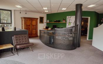 Furnished workspaces with a modern reception desk, green feature wall, and a blend of classic and contemporary furnishings at Abdis van Thornstraat 74, ideal for office space rental.