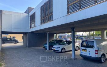 Exterior view of office building at Abdis van Thornstraat 74, Oosterhout Nb, with parking area partially shaded by modern overhang.