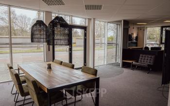 Bright office space with large windows and a wooden table with chairs at Abdis van Thornstraat 74, ideal for office space rental in Oosterhout Nb.