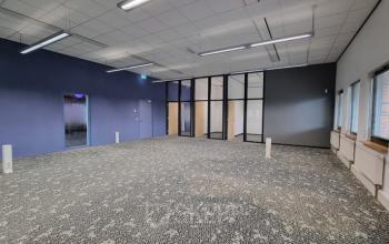 Spacious office to rent at Veengang 1, Oosterwolde, featuring patterned carpet, large windows, and ample natural light.