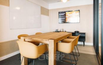 Cette salle de réunion lumineuse avec une table en bois offre une ambiance chaleureuse au boulevard Pereire