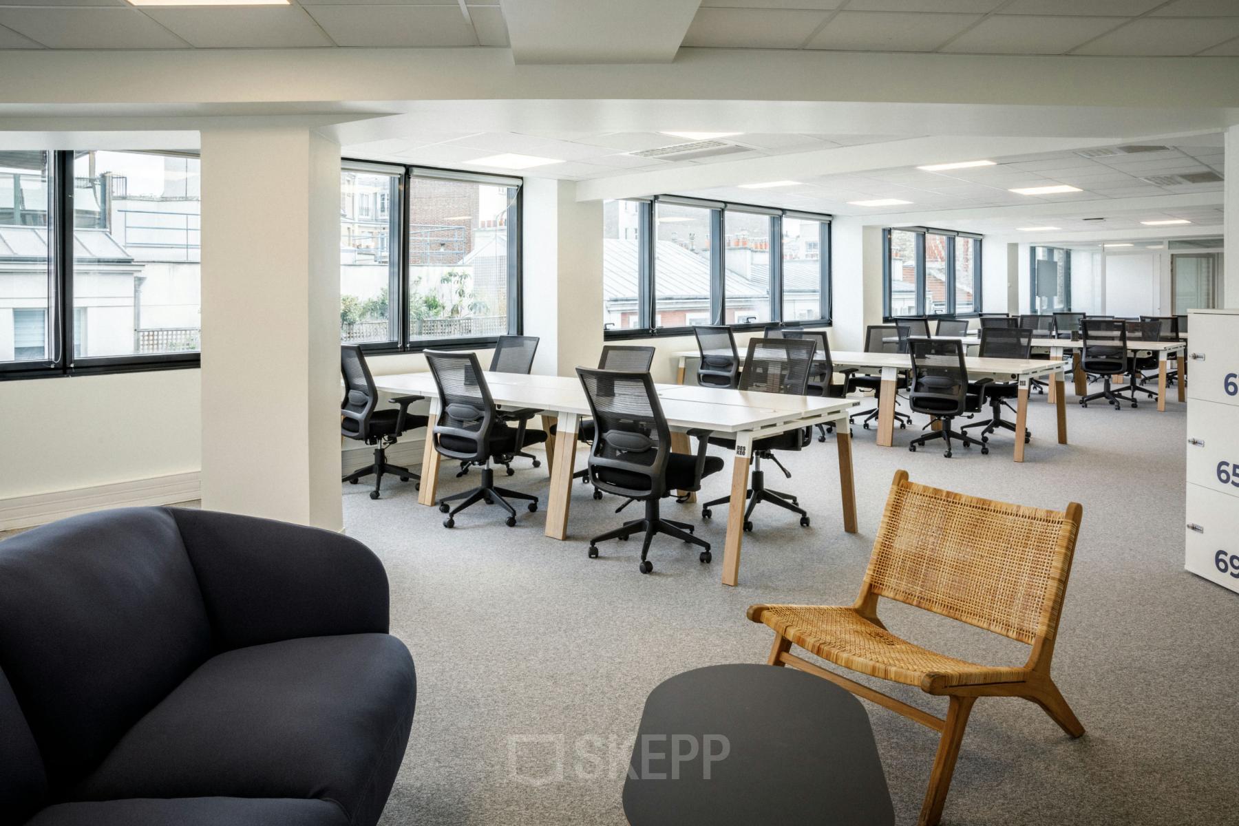 Espace de bureau à louer au Boulevard Gouvion Saint-Cyr 9, Paris 17ème, avec grandes fenêtres, chaises ergonomiques et mobilier moderne.