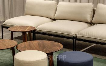 Espace lounge avec canapé moderne et tables basses en bois dans un bureau à louer à Paris 17ème, rue de Courcelles.