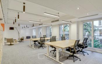 Espace de bureaux lumineux à louer à Rue de Cambacérès 24, Paris 8ème, avec plusieurs postes de travail, chaises ergonomiques et grandes fenêtres.