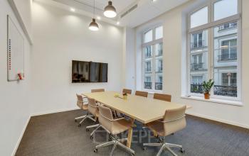 Salle de réunion moderne avec une grande table en bois, chaises ergonomiques et un écran, située au bureau à louer Rue de Cambacérès 24, Paris 8ème.
