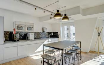 Espace de bureau à louer avec cuisine moderne et table haute dans l'immeuble de Rue de Cambacérès 24, Paris 8ème.