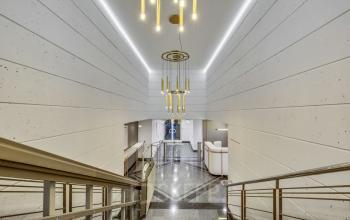 Élégant hall d'entrée du bureau à louer situé Rue de Cambacérès 24, Paris 8ème, avec escalier moderne, éclairage chic et murs clairs.