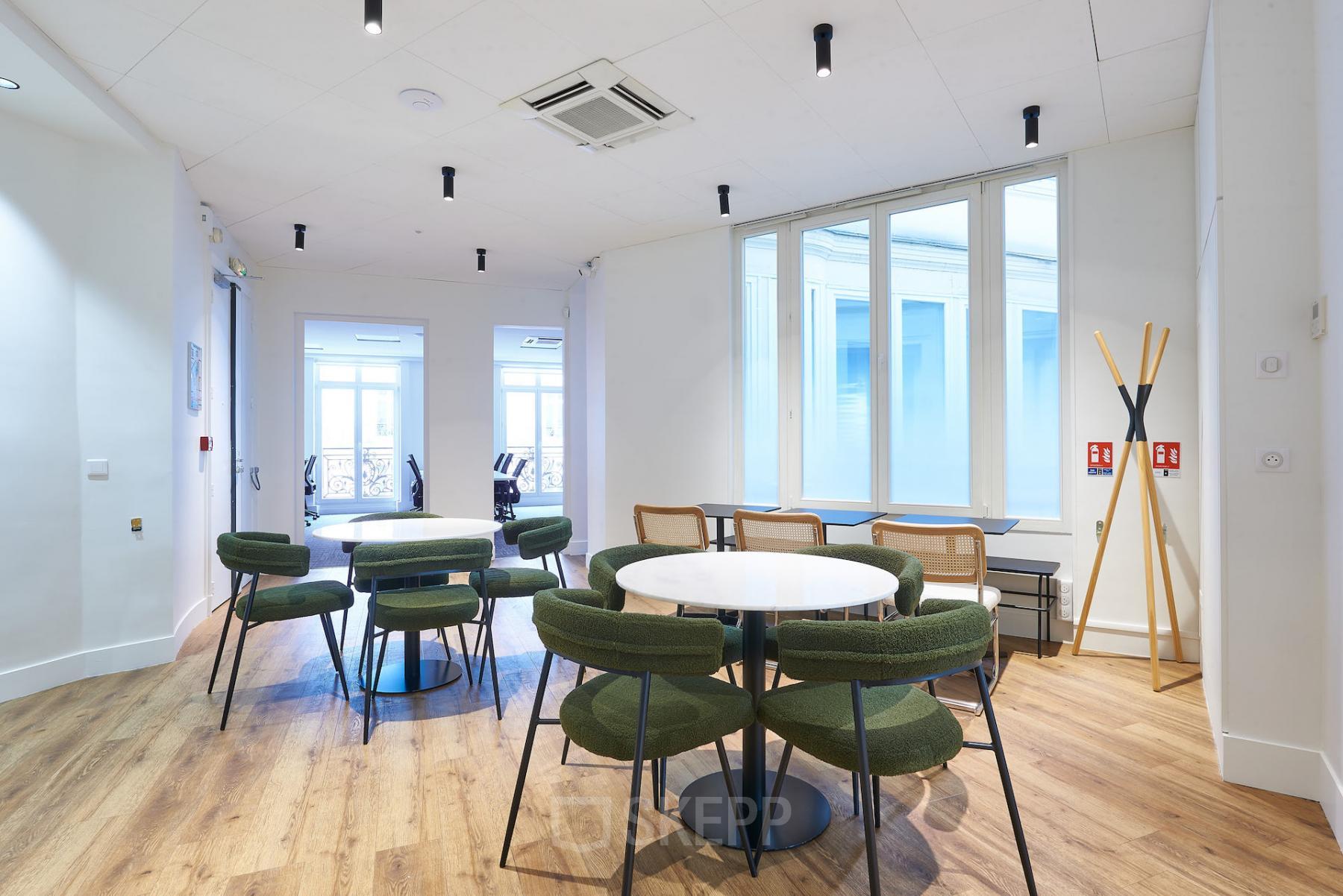 Espace de bureau à louer à rue Auber 12, Paris 9ème avec tables, chaises vertes, sol en bois et grandes fenêtres lumineuses.