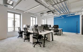 Espace de bureau à louer lumineux et moderne à rue de Provence 49, Paris 9ème, avec des bureaux équipés de chaises noires et de moniteurs.