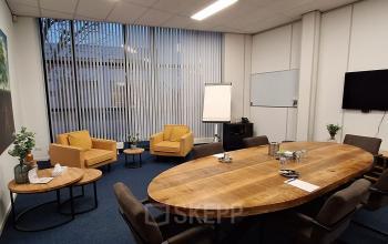 Spacious office space rental at Leeghwaterstraat 25, Reeuwijk, featuring a large wooden conference table, comfortable chairs, and modern decor, ideal for business meetings.