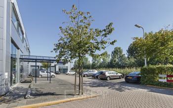Exterior view of office space available for rent at Leeghwaterstraat 25, Reeuwijk, featuring a parking area with several parked cars and modern office building facade.