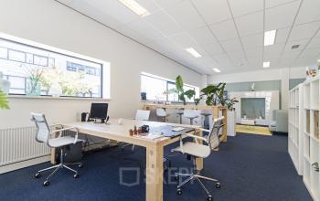 Bright office space at Leeghwaterstraat 25, Reeuwijk, featuring wooden desks, ergonomic chairs, and large windows. Ideal for rent office space seekers.