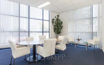Bright office space rental in Reeuwijk with large windows, white chairs, and greenery, perfect for meetings or collaborative work.