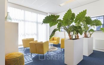 Bright office space at Leeghwaterstraat 25 in Reeuwijk featuring yellow chairs, blue carpet, and large plants ideal for office space rental.