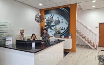 Reception area at Leeghwaterstraat 25, Reeuwijk, displaying a welcoming desk with staff assisting guests, ideal for office space rental.