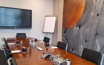Conference room at Leeghwaterstraat 25, Reeuwijk, featuring a large wooden table, chairs, screen, and minimalistic wall decor. Ideal office space rental for meetings.