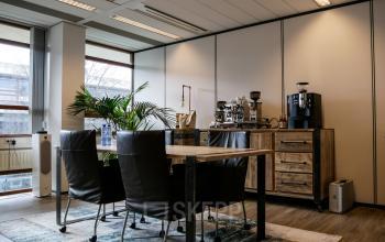 Furnished office space with a wooden meeting table, black chairs, and coffee machines at Ericssonstraat 2, Rijen, available for rent.