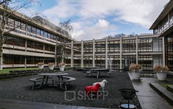 Outdoor courtyard of the office space rental at Ericssonstraat 2, Rijen, featuring modern architecture with exterior picnic tables.