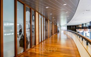 Curved hallway with wooden flooring and glass-walled offices at Ericssonstraat 2, Rijen, available for office space rental.