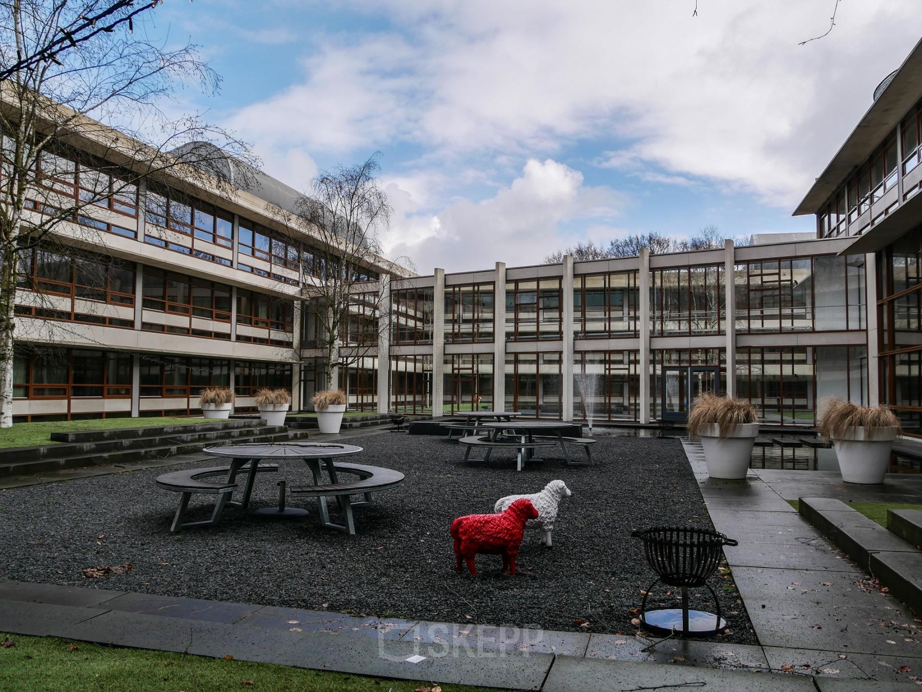Outdoor courtyard of the office space rental at Ericssonstraat 2, Rijen, featuring modern architecture with exterior picnic tables.