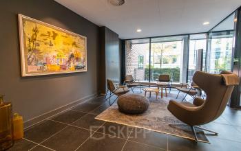 Modern furnished office space with stylish chairs and a large window view at Laan van Vredenoord 33, suitable for rent office space.