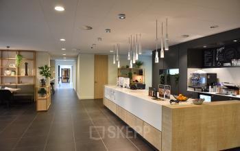 Modern office reception area at Laan van Vredenoord 33, Rijswijk, perfect for office space rental with a welcoming desk and coffee station.