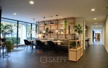 Spacious, modern office lounge with elegant furnishings in Rijswijk, ideal for office space rental, featuring ample natural light and greenery.