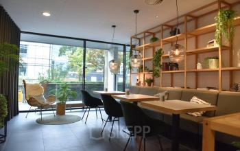 Furnished office space rental with modern decor, hanging lights, and seating at Laan van Vredenoord 33, Rijswijk.