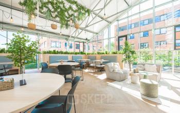 Modern office interior at Lange Kleiweg 50-62, Rijswijk, featuring ample natural light, green decor, and stylish furnishings, perfect for office space rental.