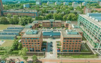 Aerial view of office buildings with a central courtyard at Lange Kleiweg 50-62, Rijswijk, surrounded by greenery and urban landscape, highlighting opportunities for office space rental.
