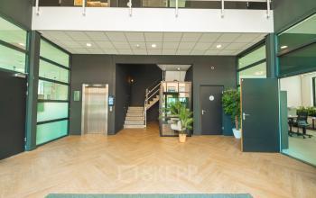 Spacious office interior at Lange Kleiweg 50-62, Rijswijk, featuring modern design with elevator access, a staircase, and meeting rooms. Ideal for office space rental.