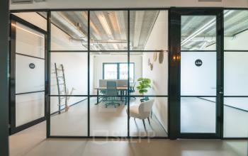 Modern office space rental at Lange Kleiweg 50-62, Rijswijk, featuring a stylish glass-walled room with minimalistic furnishings, a desk, and a cozy chair, creating a bright and inviting environment.