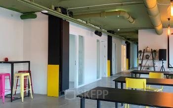 Bright and modern office space with yellow chairs and black tables, ideal for those seeking office space rental at Volmerlaan 7, Rijswijk.