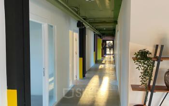 Modern and illuminated corridor inside Volmerlaan 7, showing a potential office space rental in Rijswijk with multiple doors leading to offices.