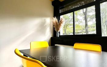 Bright office space at Volmerlaan 7, Rijswijk, featuring a yellow ceiling and chairs around a dark table, available for office space rental.