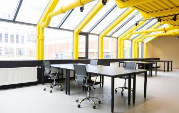 Bright office space with yellow beams and large windows at Volmerlaan 7, Rijswijk, ideal for those seeking office space rental.