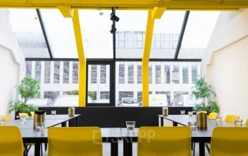 Bright office space at Volmerlaan 7, Rijswijk with large windows, yellow accents, and desks set up for a meeting, available for rent.