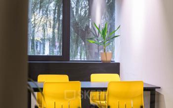 Office space for rent at Volmerlaan 7, Rijswijk, featuring bright yellow chairs around a table with a potted plant against a window backdrop.