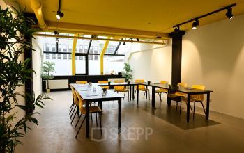 Bright office space at Volmerlaan 7, Rijswijk, featuring yellow accents, large windows, and modular desks, ideal for office space rental. Perfect for dynamic setups in this airy, inviting office to rent.