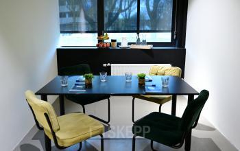 Cozy office space to rent at Volmerlaan 7, Rijswijk, featuring a table with four chairs and natural light from the window.